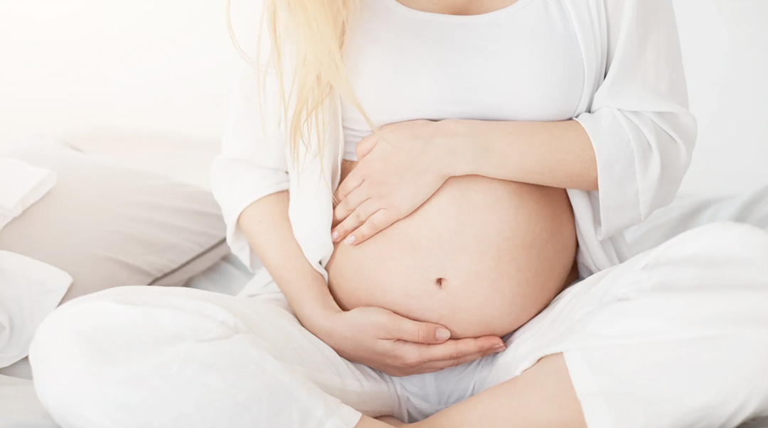 Mujer embarazada con sus manos sobre el vientre en actitud de espera